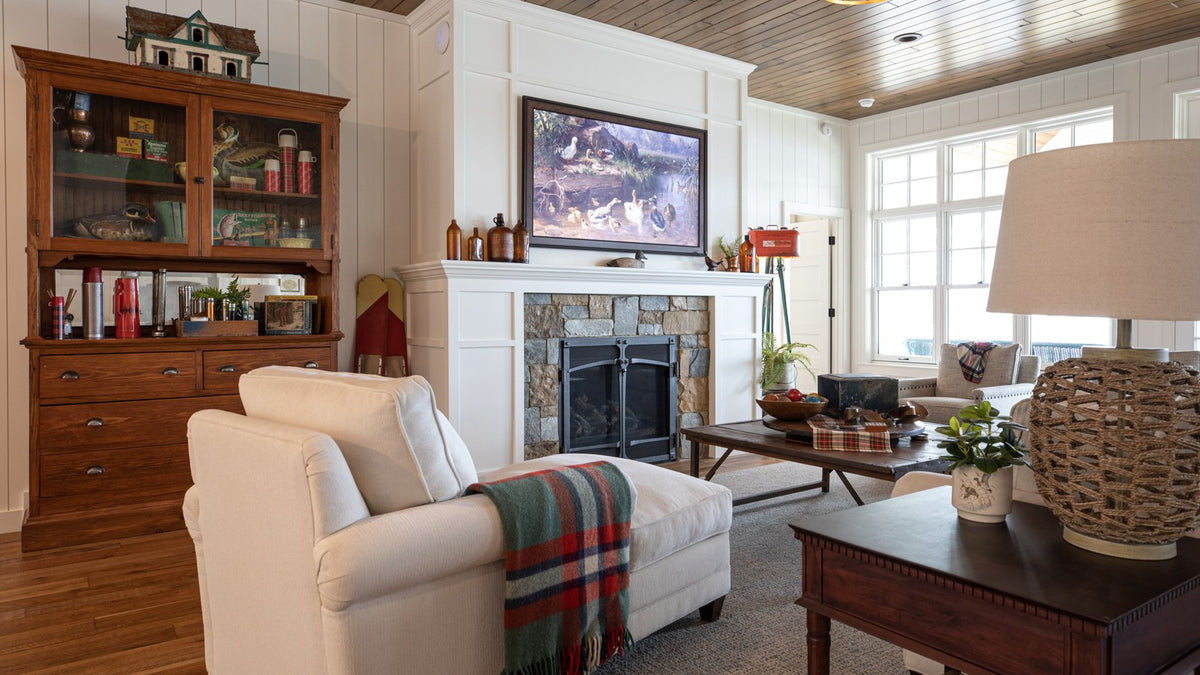 White upholstered chaise with a plaid throw by a stone fireplace and a wood display hutch, Duck Lake Landing project