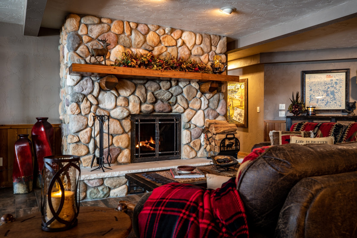 Living room with fieldstone fireplace and plaid throw, Antler Lake Lodge project, Northern Wisconsin