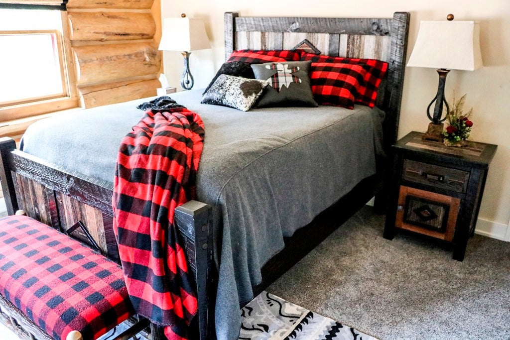 Log bedroom with a dark wood bed and a red buffalo-check throw, Northpoint project, Northern Wisconsin