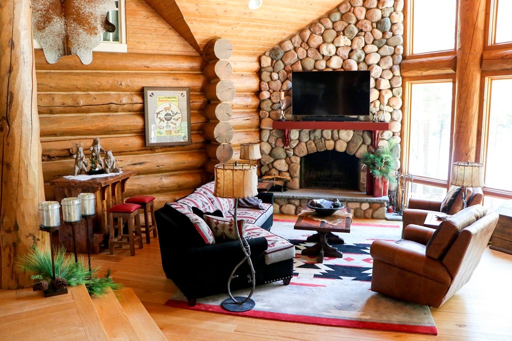 Log living room with a stone fireplace and leather club chairs, Northpoint project, Northern Wisconsin