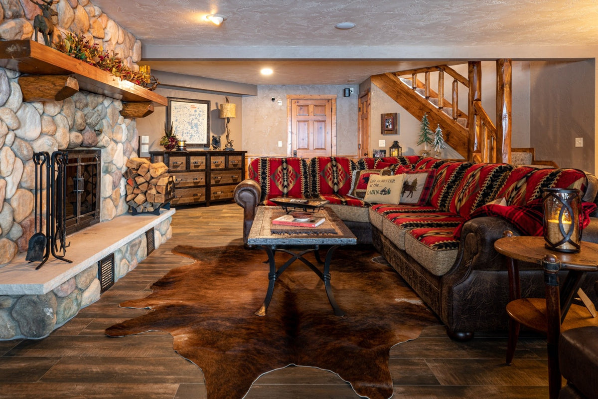 Stone fireplace living room with a red sofa and a cowhide rug, Antler Lake Lodge project, Northern Wisconsin