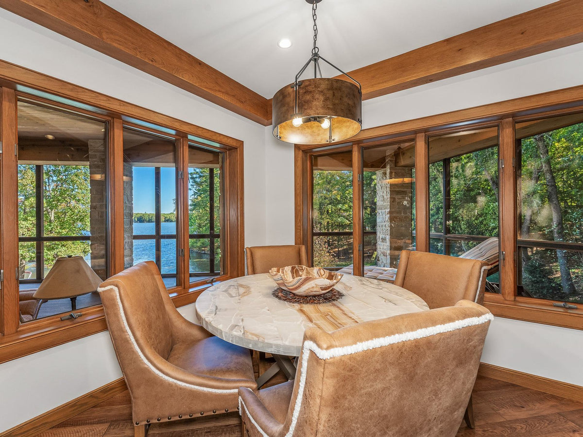 Round dining table with leather chairs by windows looking onto the lake, Copperline project, Eagle River, Wisconsin