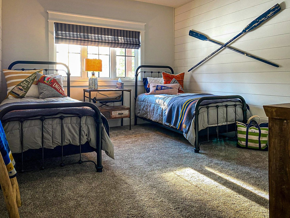 Bunk-style guest bedroom with two iron beds and crossed oars on the wall, Dreamer's Lake project, Central Wisconsin