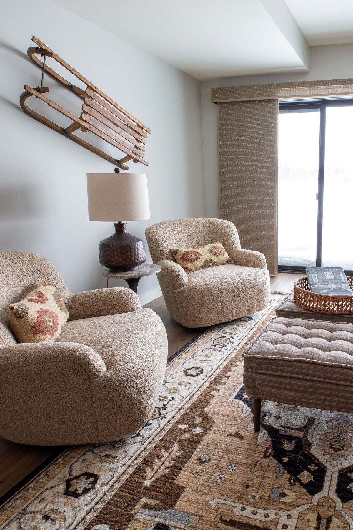 Sitting area with curved boucle chairs, a patterned rug and a vintage sled on the wall, Black Diamond project