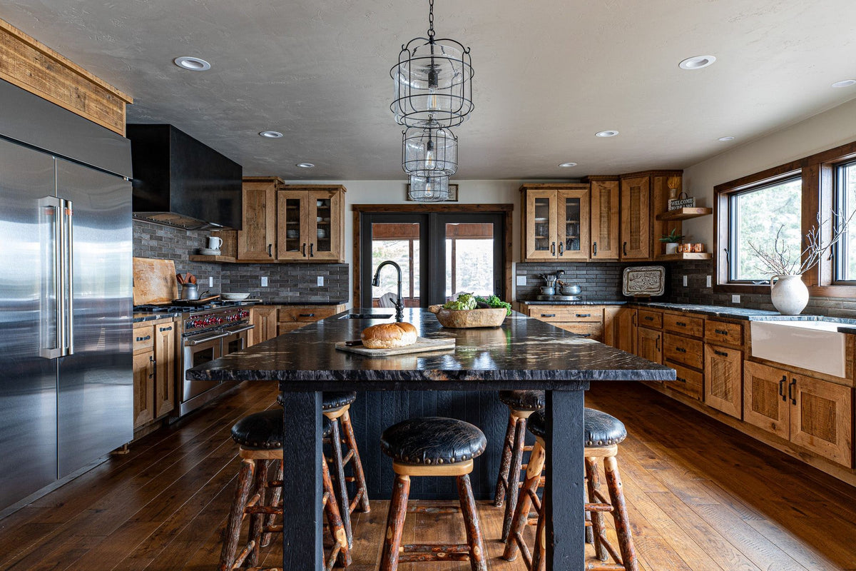 Kitchen with a dark island, glass pendants and wood cabinets, Timberline project, Northern Wisconsin