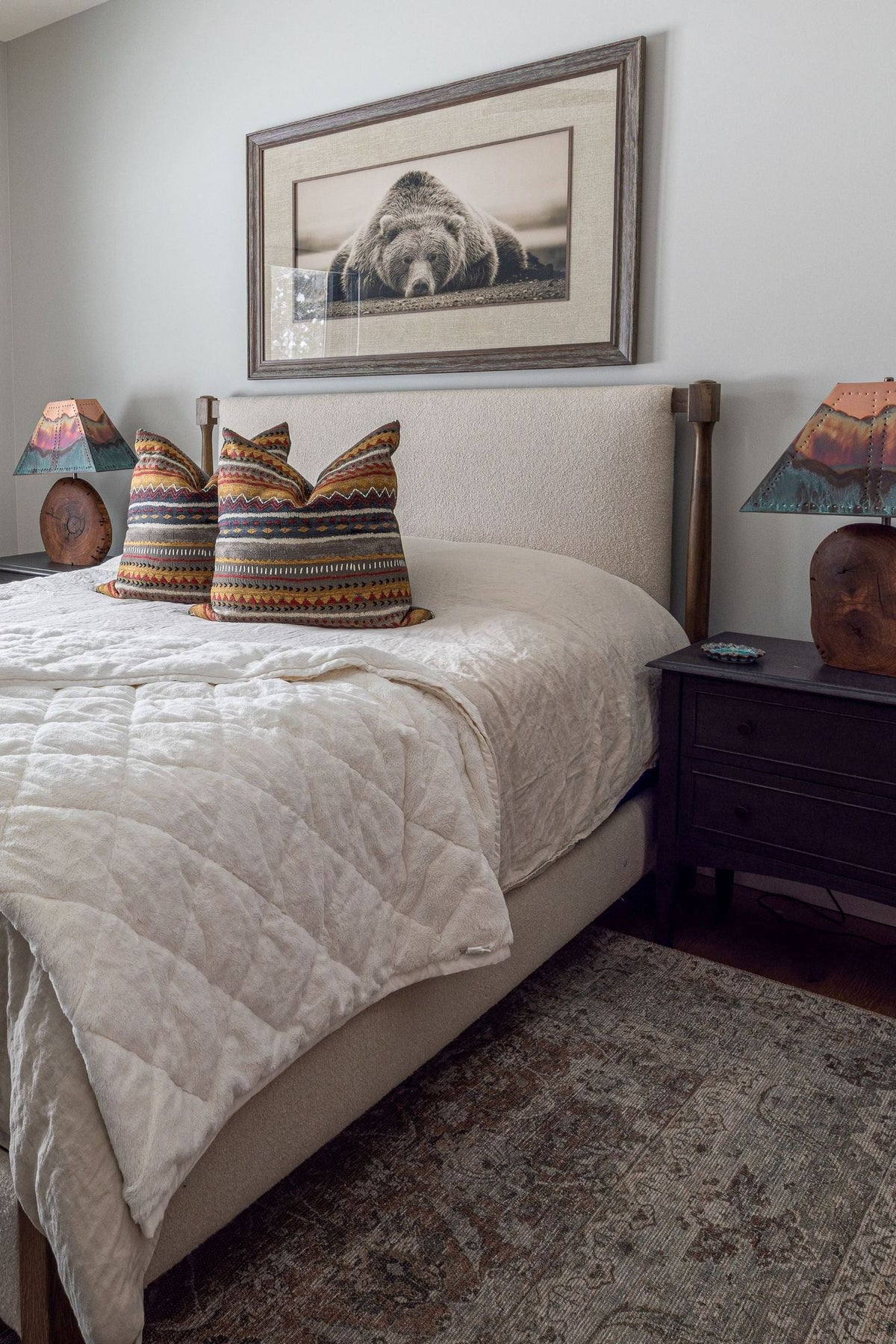 Bedroom with an upholstered bed, a dark nightstand and a framed bear photo, Black Diamond project