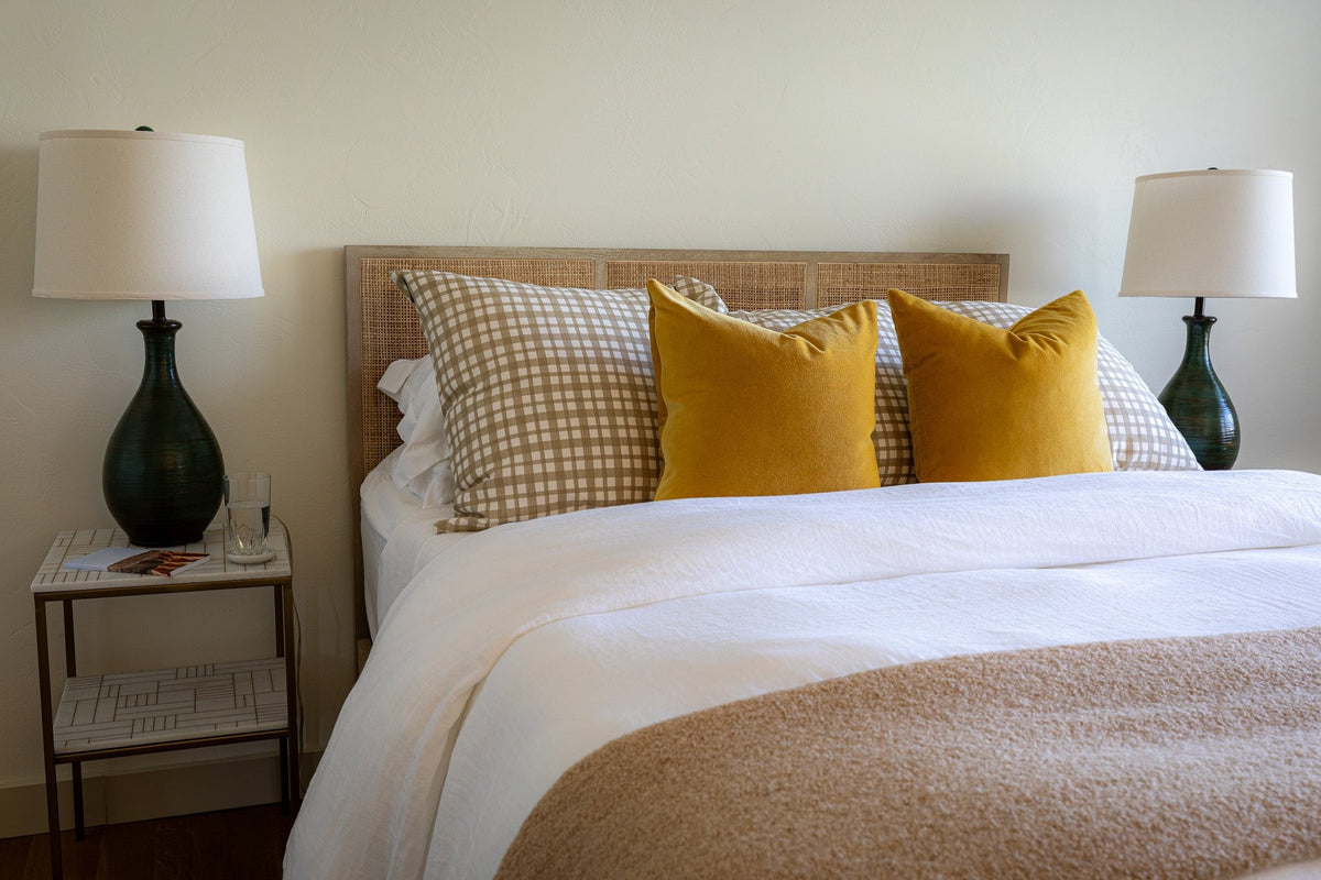 White bedroom with mustard pillows and dark ceramic lamps, Driftwood Shores project, Northern Wisconsin