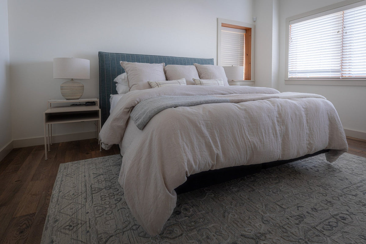White bedroom with a blue upholstered headboard and soft linen bedding, Driftwood Shores project, Northern Wisconsin