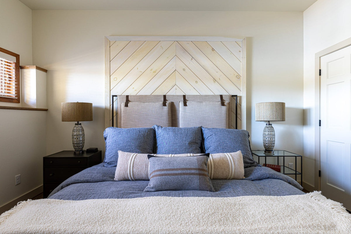 Bedroom with a whitewashed chevron plank headboard and blue bedding, Driftwood Shores project, Northern Wisconsin