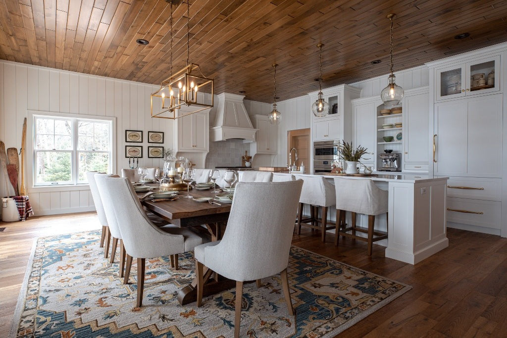 White dining room with a long table, upholstered chairs and a wood ceiling, Duck Lake Landing project, Eagle River, Wisconsin