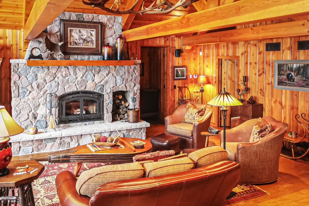Living room with a stone fireplace, leather seating and a round wood coffee table, Pointed Pines project, Northern Wisconsin
