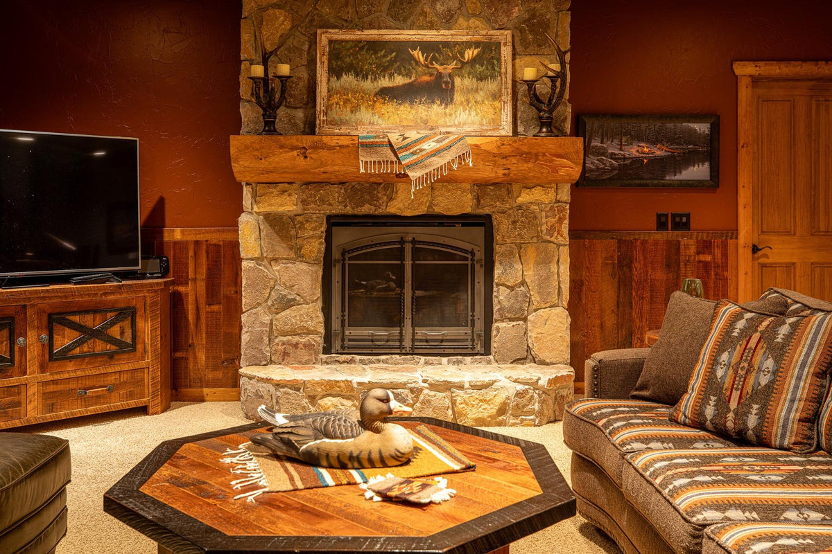 Living room with a stone fireplace, an octagonal wood coffee table and a striped sofa, Big Hills project