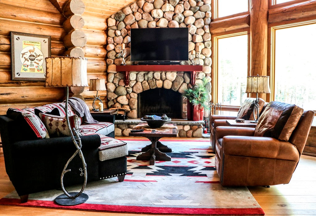 Log-walled living room with river-rock fireplace and leather seating, Northpoint project, Northern Wisconsin