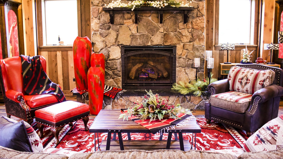 Red leather wingback and ottoman and a Native-pattern armchair on a red rug by a stone fireplace, Rock and Roll Barn project