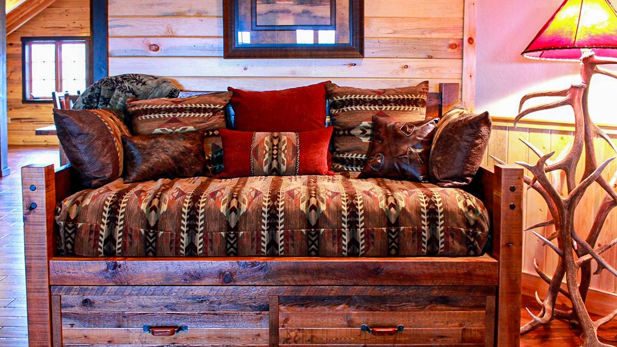 Barnwood daybed with Navajo-pattern cushions, red pillows and an antler lamp, Beresford Lodge project